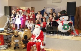 Na zdjęciu widzimy Świętego Mikołaja rozdającego prezenty dzieciom w Domu Ludowym w Zręcinie