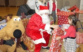 Na zdjęciu widzimy Świętego Mikołaja rozdającego prezenty dzieciom w Domu Ludowym w Zręcinie